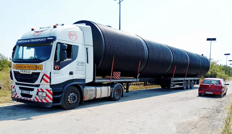 White IVECO marked for abnormal transport hauling a large conical steel section
