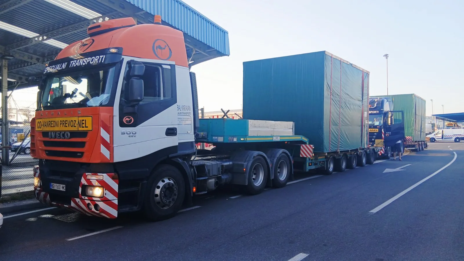 Orange IVECO marked Convoi Exceptionnel hauling green container modules