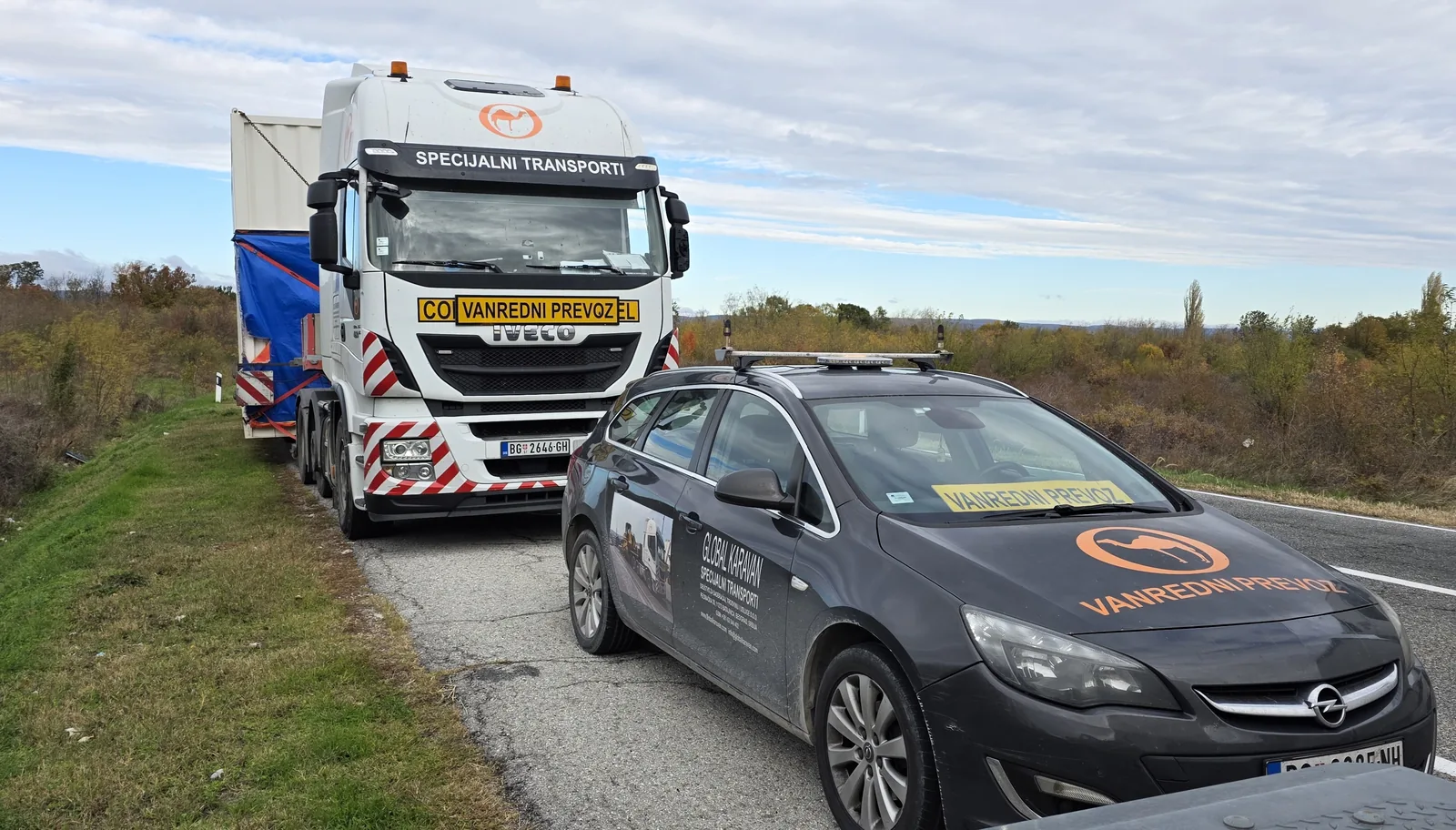 Pilot escort vehicle marked for abnormal transport leading a tractor with oversized cargo