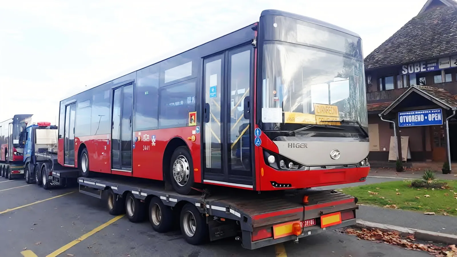 Red city bus loaded onto a lowboy trailer during a special transport operation