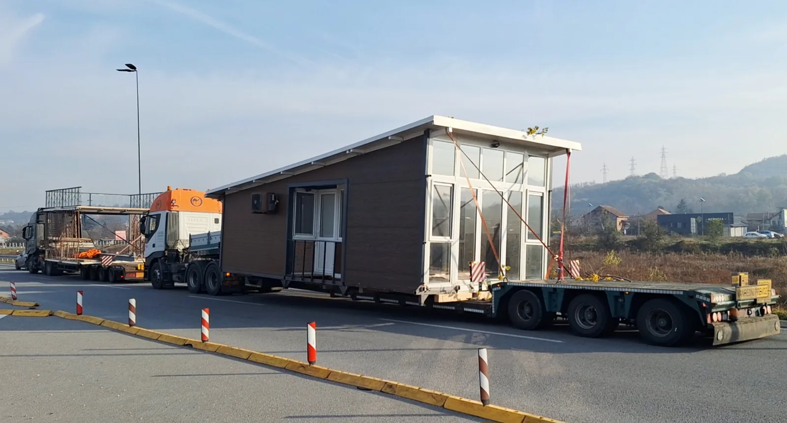 Prefabricated house with a glazed facade transported on a lowboy trailer